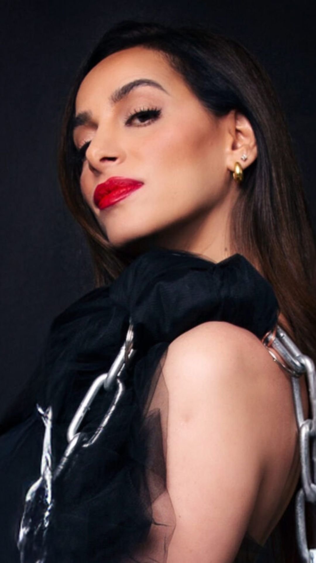 YAEL JAMES wearing black tulle and silver chains against a dark studio background, in a portrait crop for mobile.